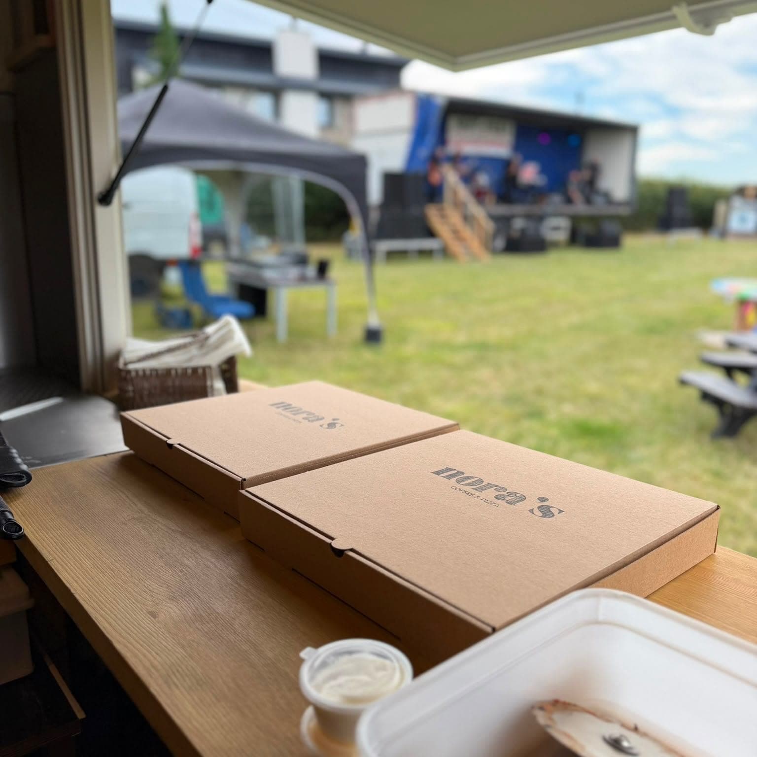Nora’s pizza boxes on the counter, looking out over an event field