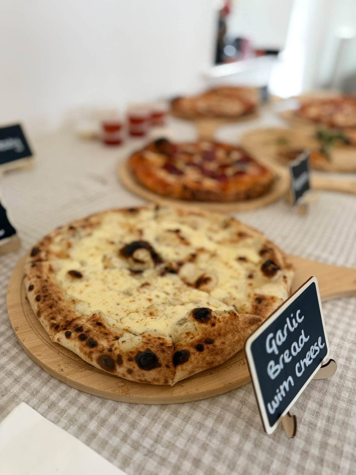 Cheesy garlic bread and sourdough pizzas laid out on wooden boards at an event