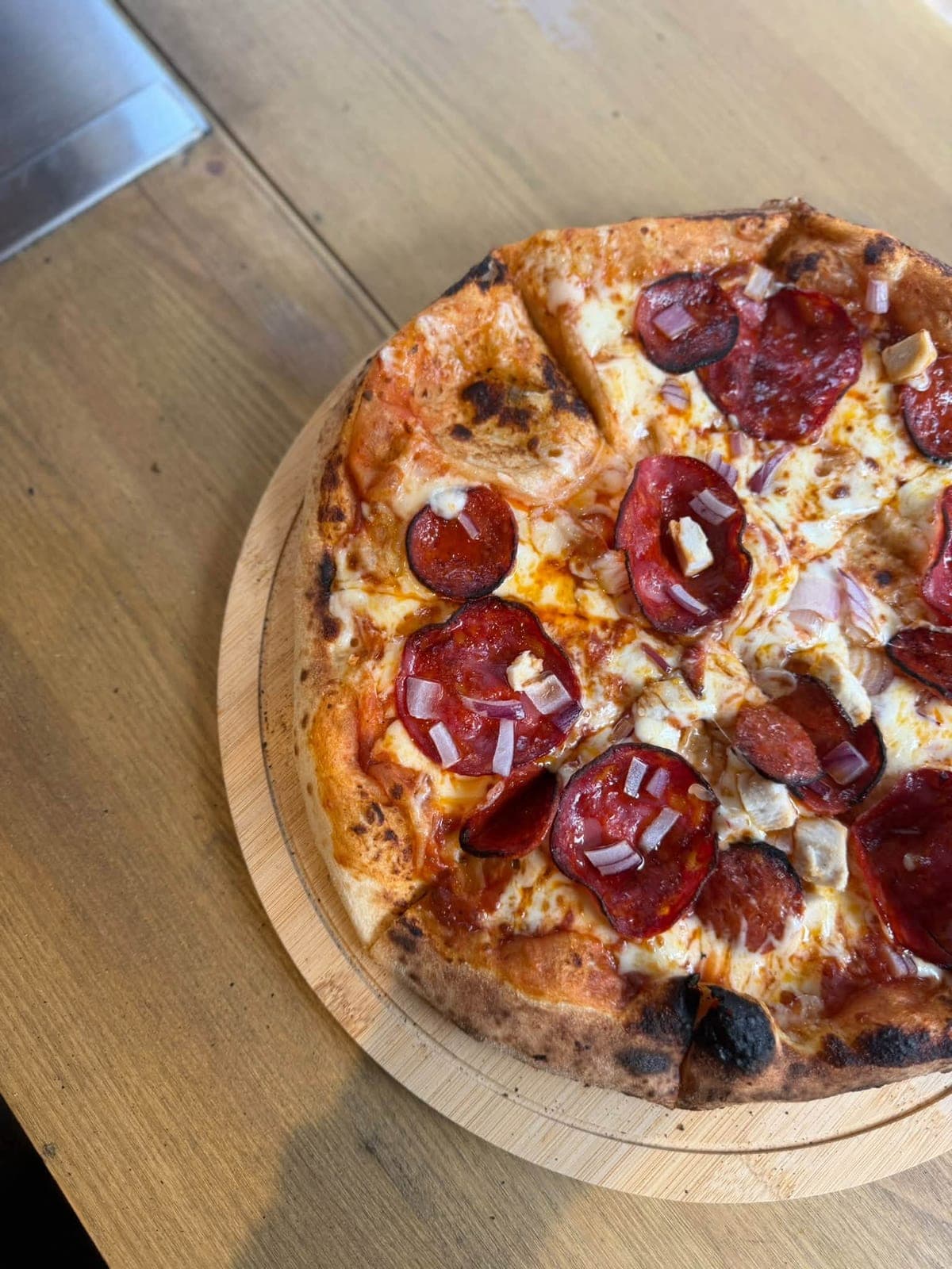 Sourdough pizza topped with pepperoni, chorizo, chicken and red onion