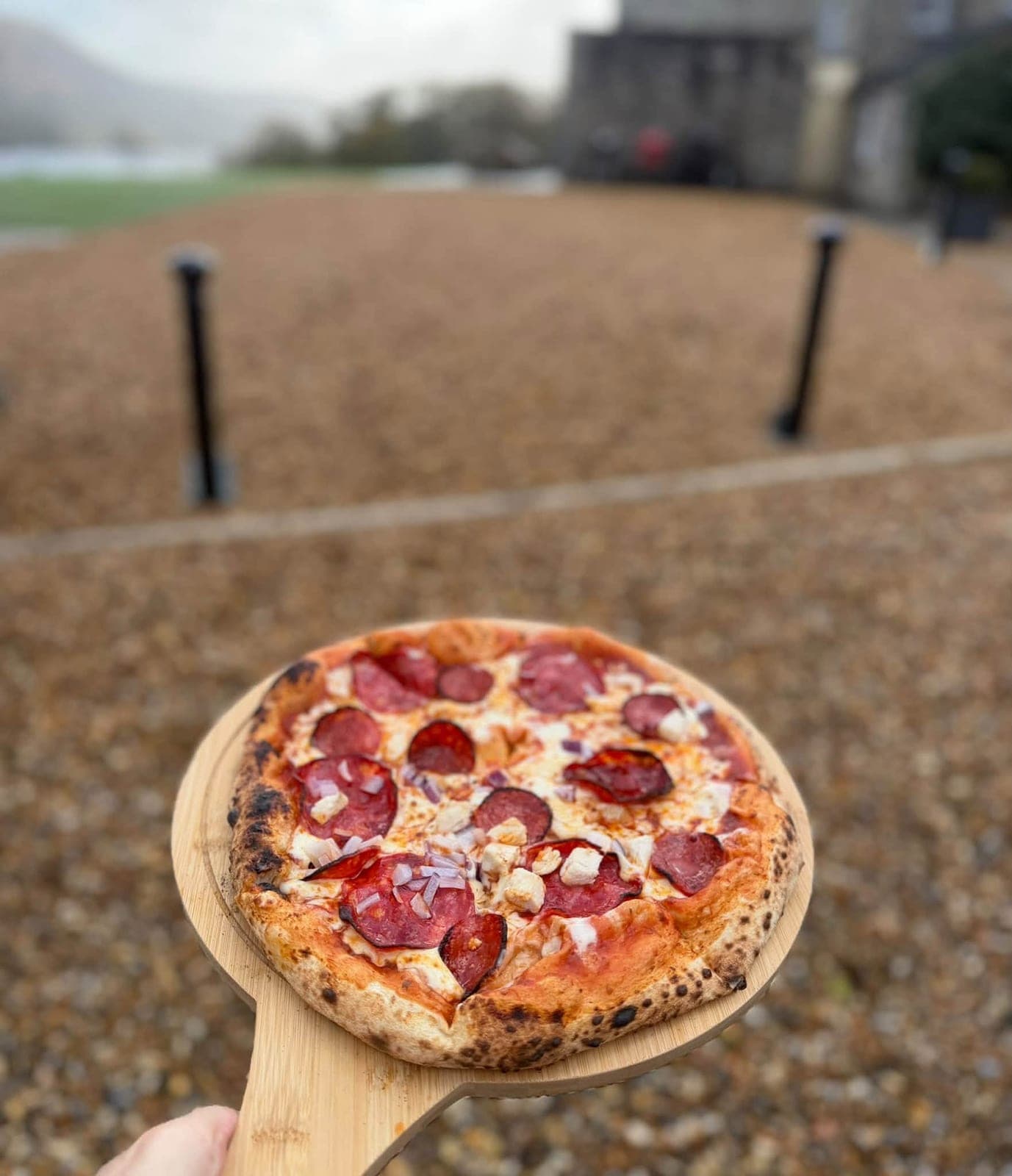 Pepperoni sourdough pizza held up on a wooden peel
