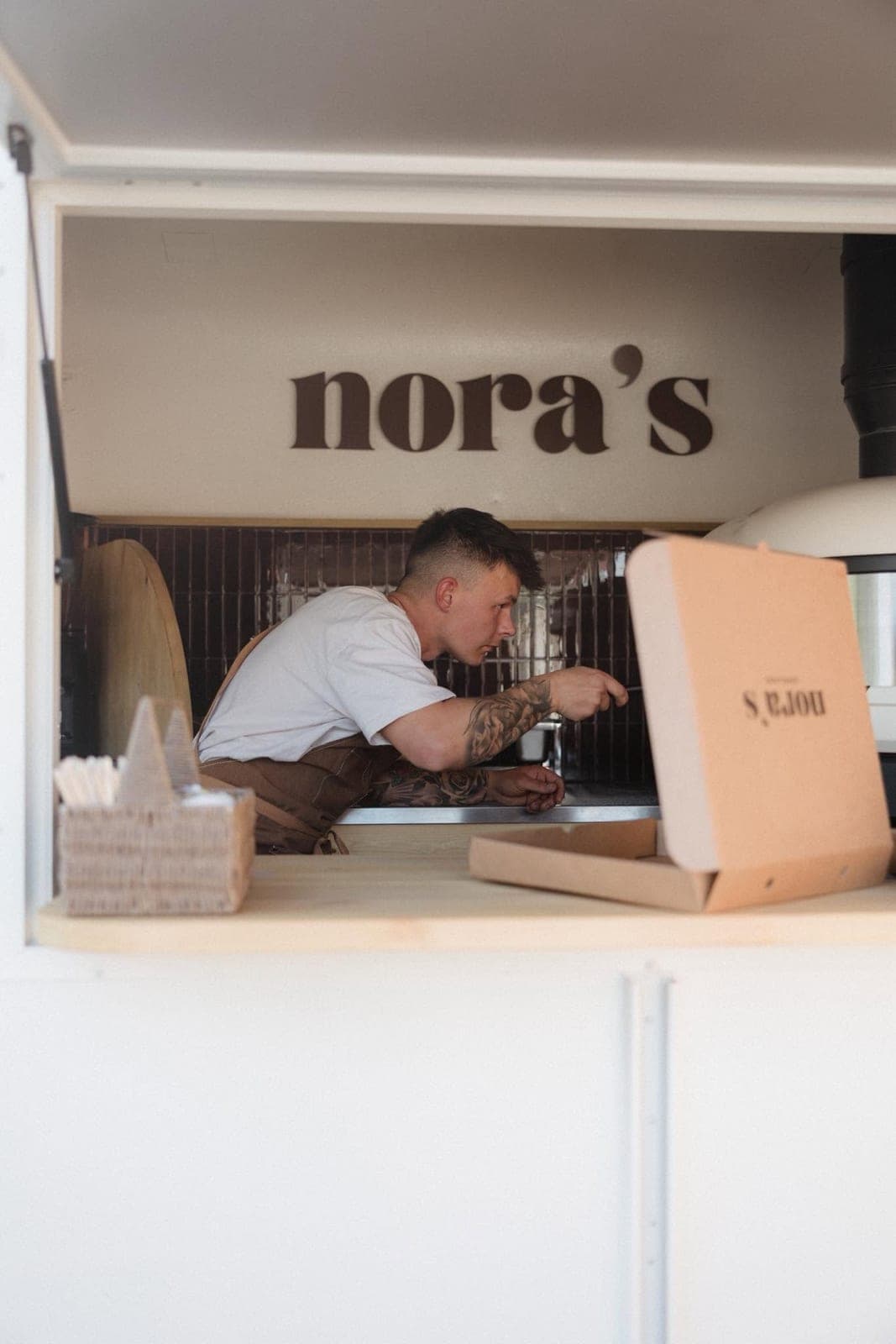 Boxing up a pizza at the serving hatch of Nora’s trailer