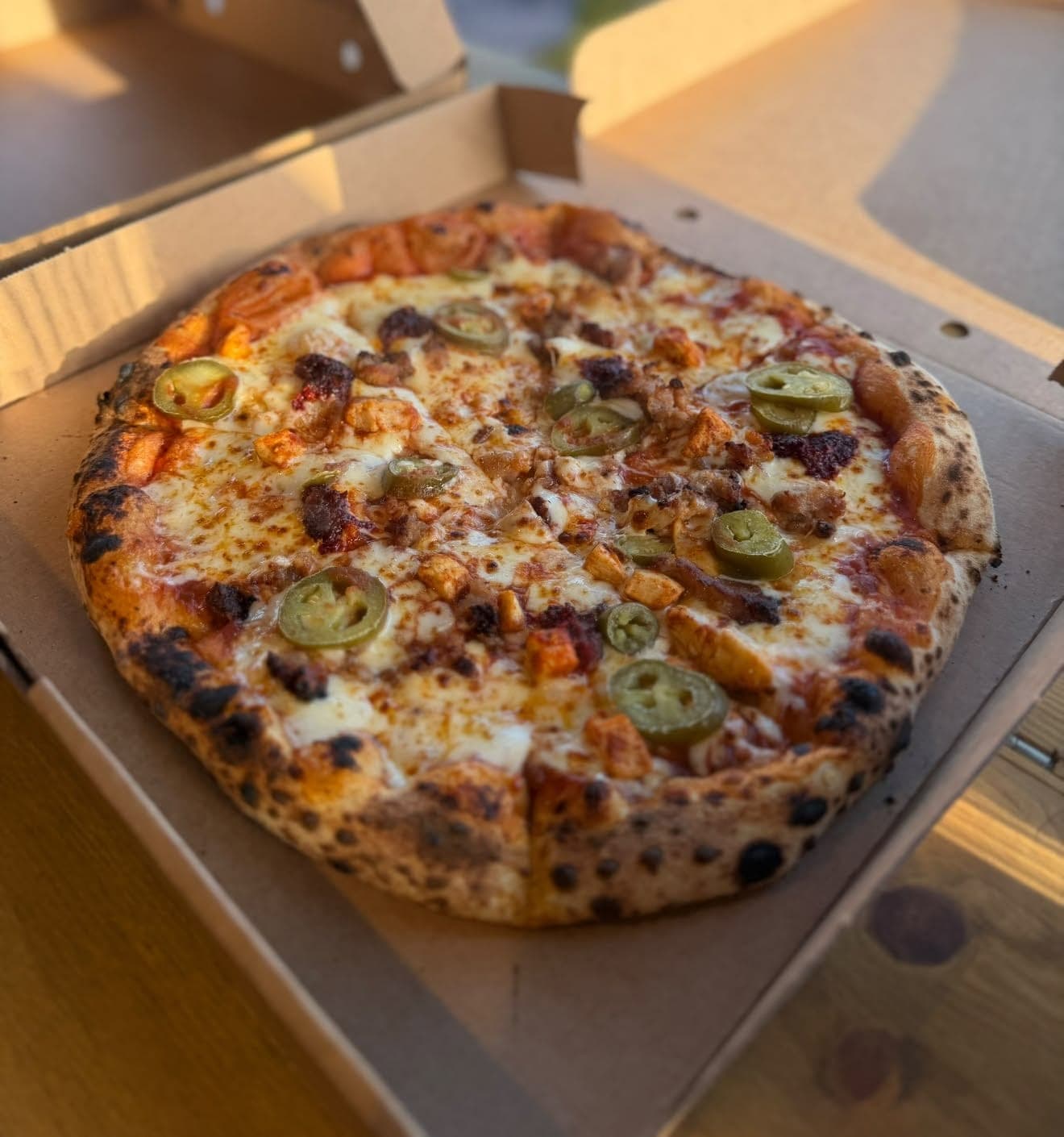 Spicy sourdough pizza with chicken and jalapeños in a takeaway box