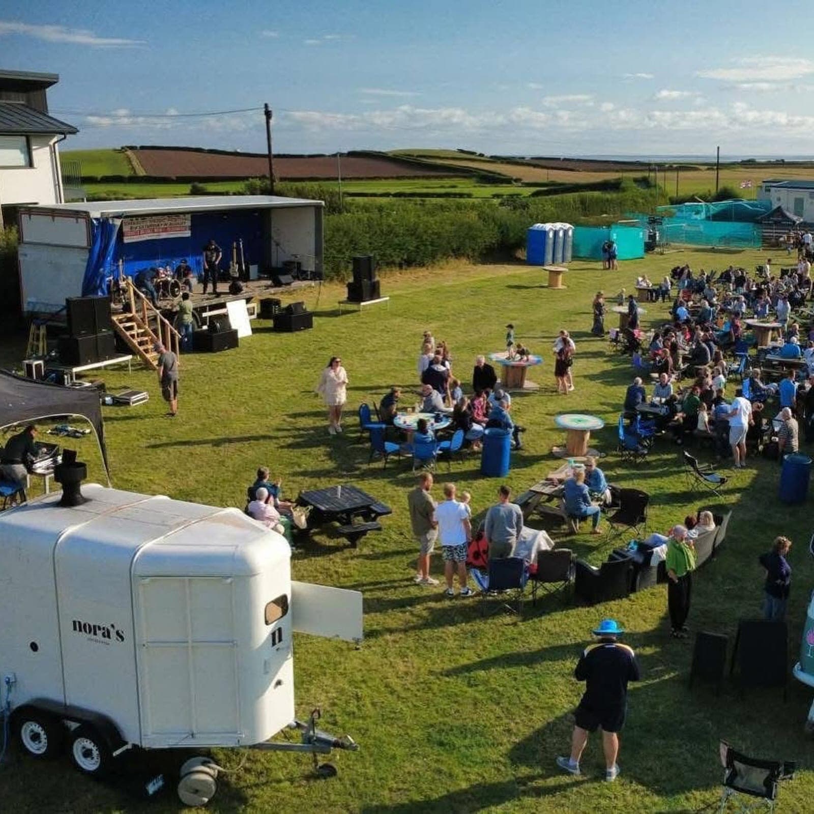 Nora’s pizza trailer at a busy outdoor event with a stage and crowd